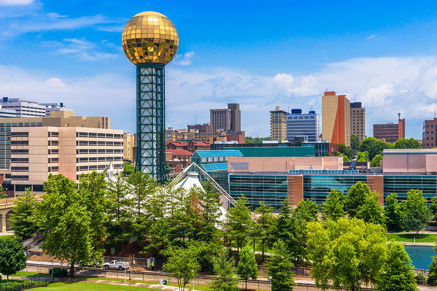 About Our Agency - Downtown Knoxville, Tennessee Skyline on a Sunny Day with Trees in the Foreground