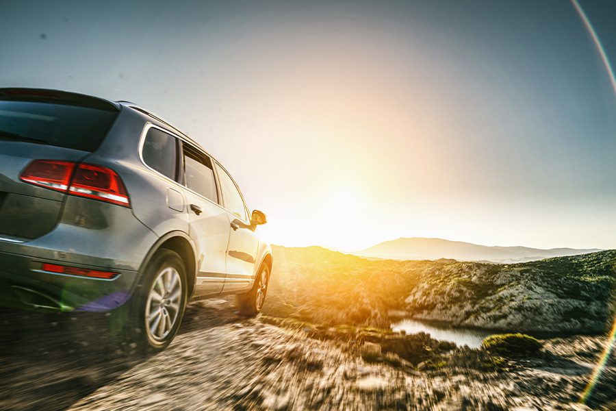 Personal Insurance - Closeup View of an SUV car in Mountain Landscape at Sunset